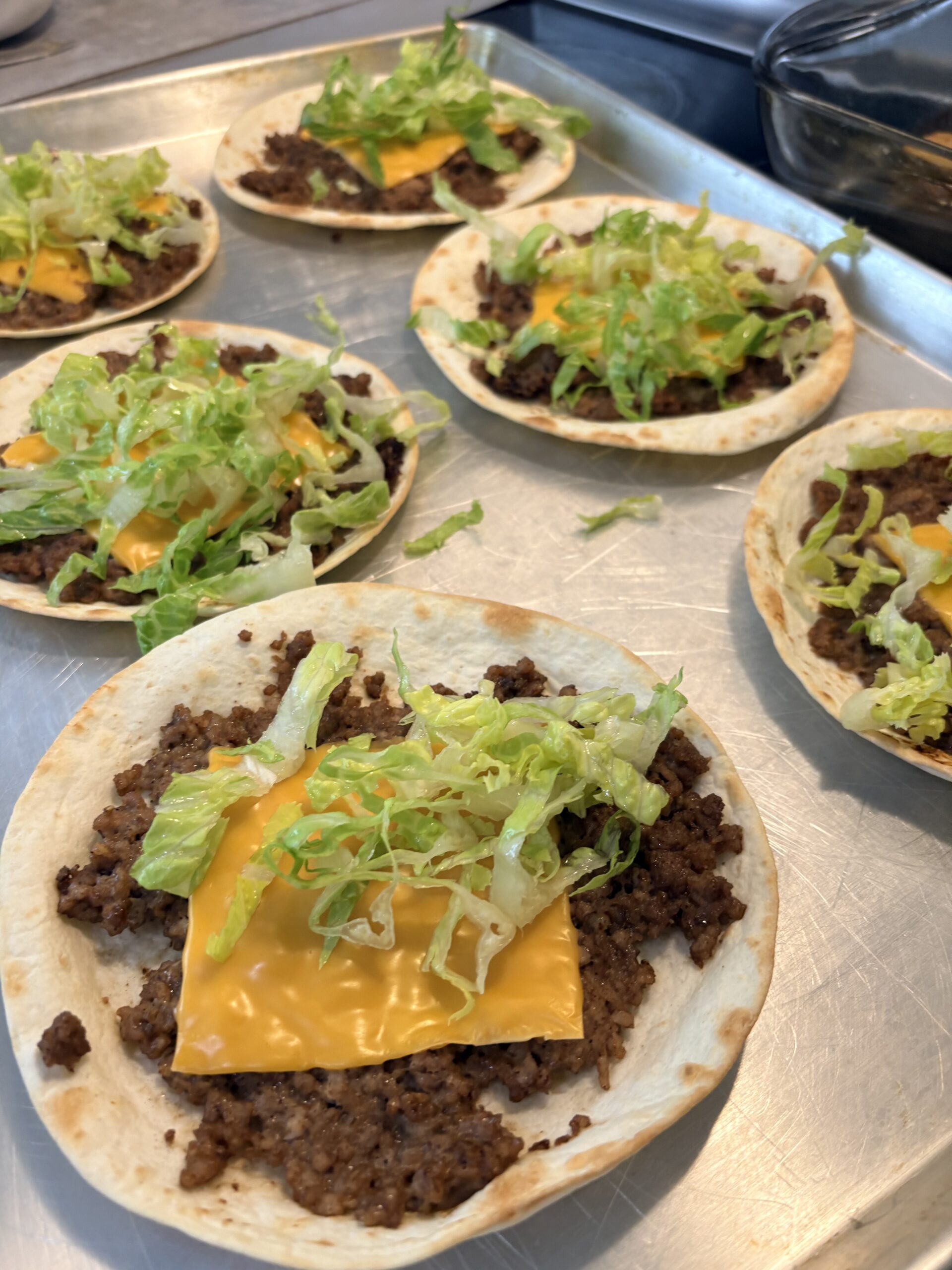 Open cheeseburger wraps topped with meat, melted cheese, and lettuce